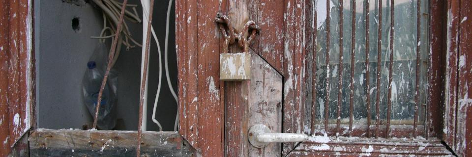 Lock on an old door with a broken window.