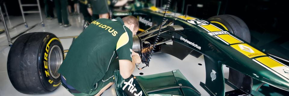 Formula 1 Team Lotus mechanic working on a race car.
